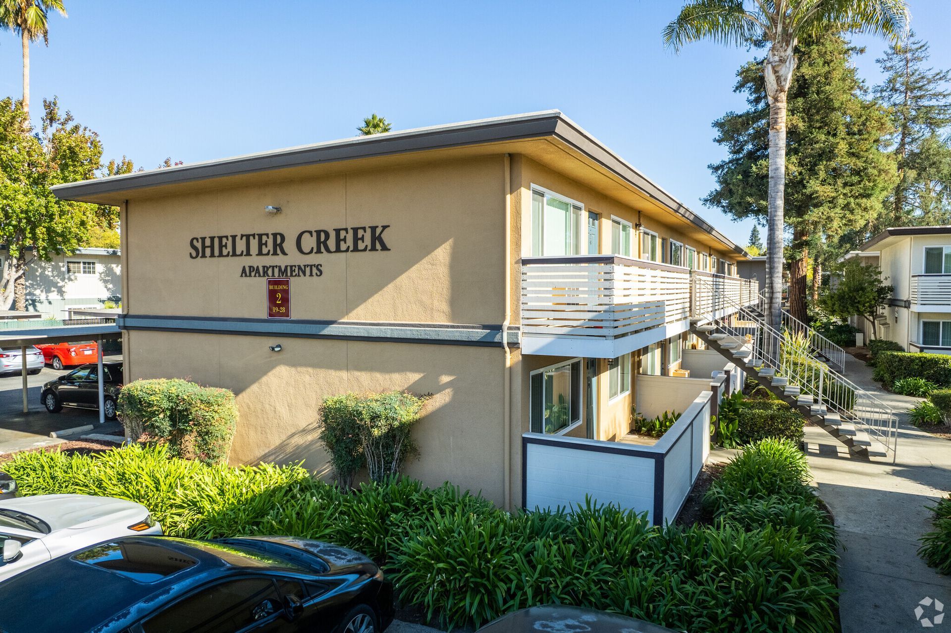 A shelter creek apartment building with cars parked in front of it