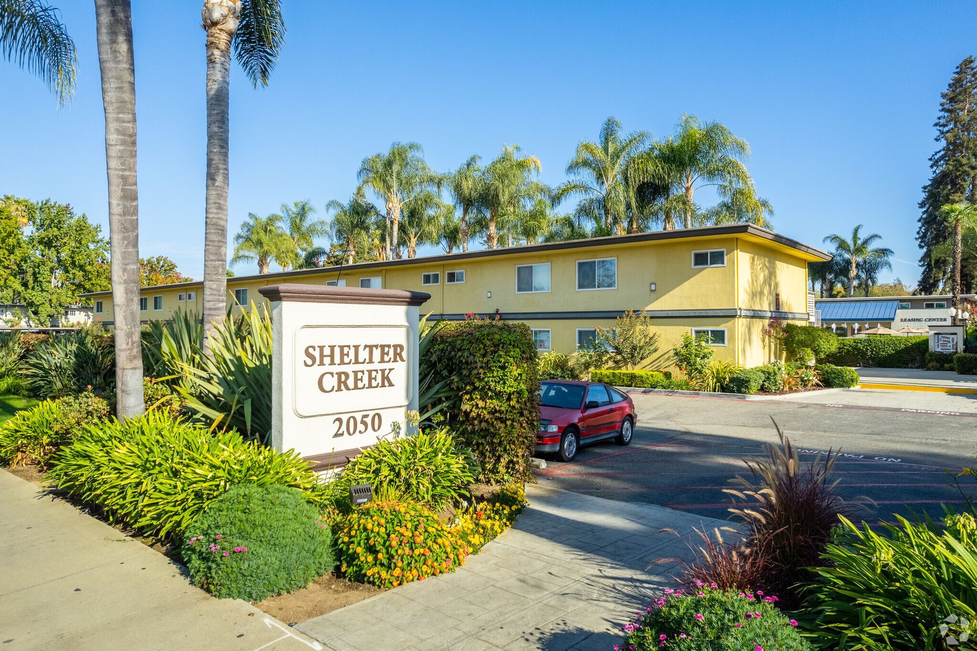 A red car is parked in front of a shelter creek sign