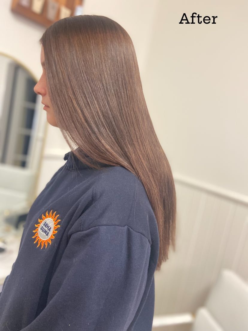 Woman with straight, brown hair after a salon treatment, wearing a navy sweater.