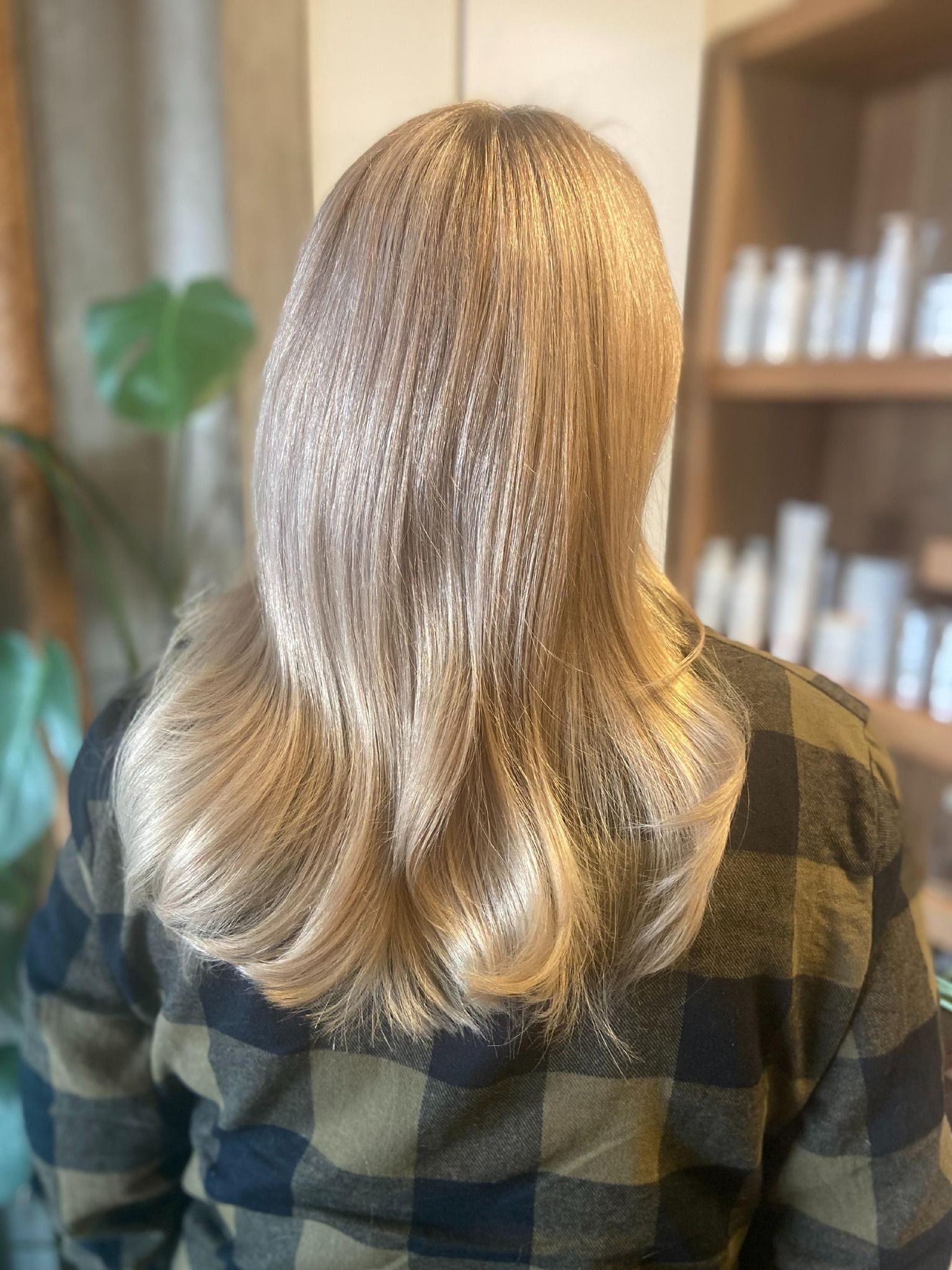 Woman with crimped blonde hair, wearing a plaid shirt, in a salon.