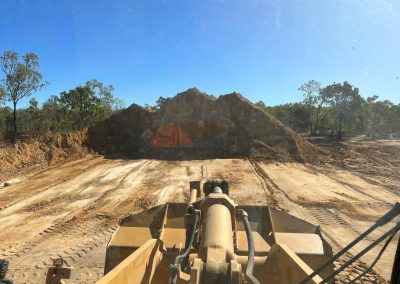 A bulldozer pushing earth in a construction zone under a blue sky, trees in the background.