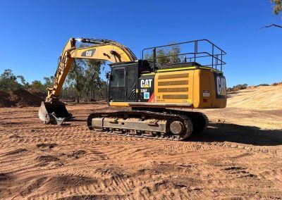 Yellow Caterpillar excavator on brown earth, under a blue sky.
