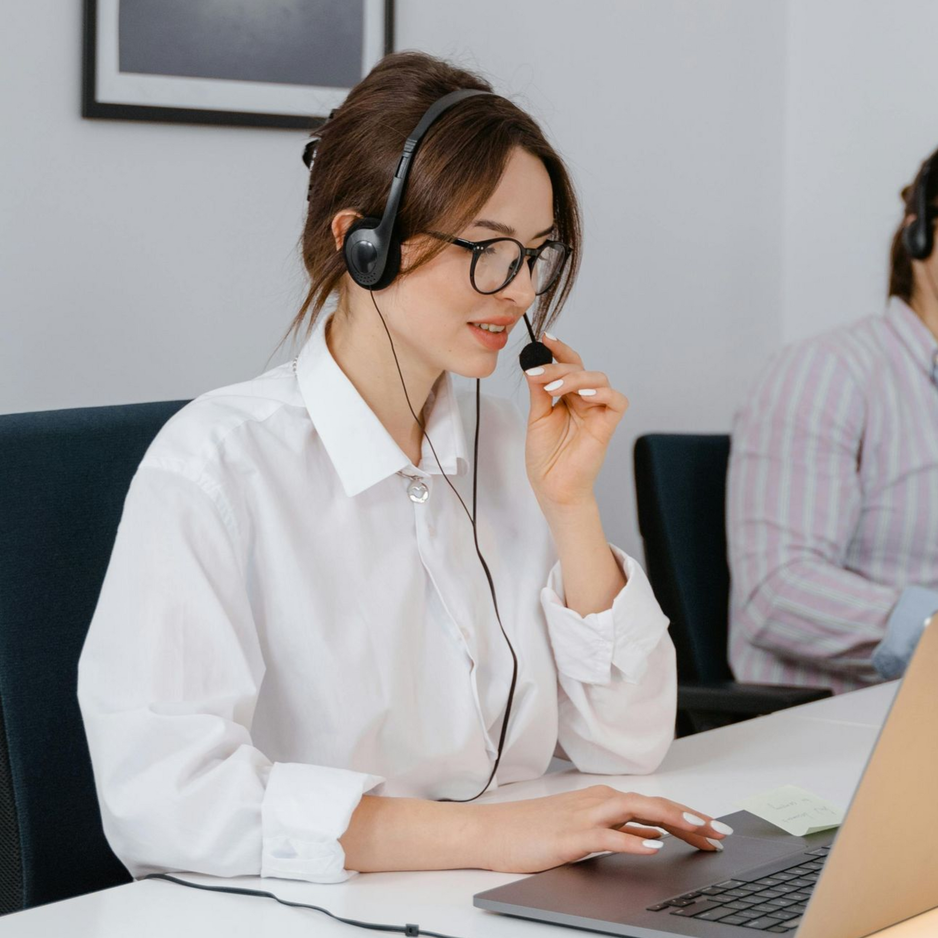 A woman wearing glasses and a white shirt is smiling for the camera.