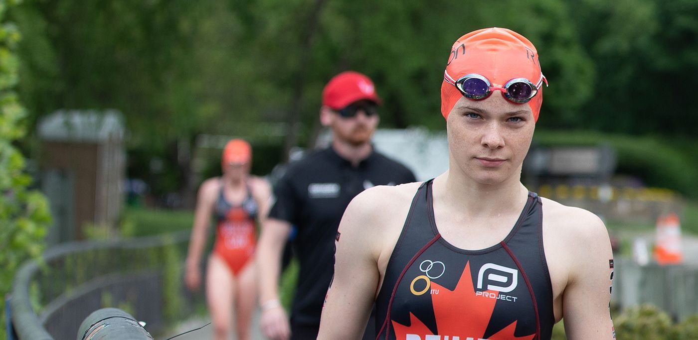 A woman wearing a swim cap and goggles is walking across a bridge