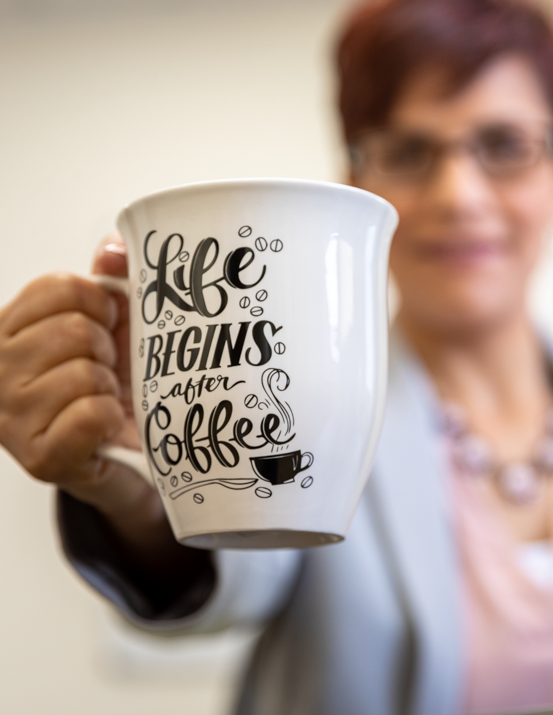 A woman is holding a mug that says life begins after coffee