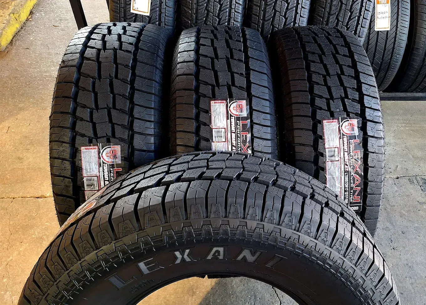 Several new truck tires with textured treads, stacked vertically.