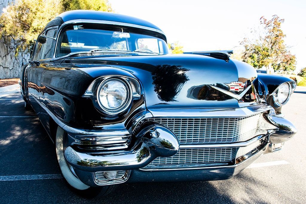 Black vintage Cadillac with chrome accents, parked in an outdoor setting.