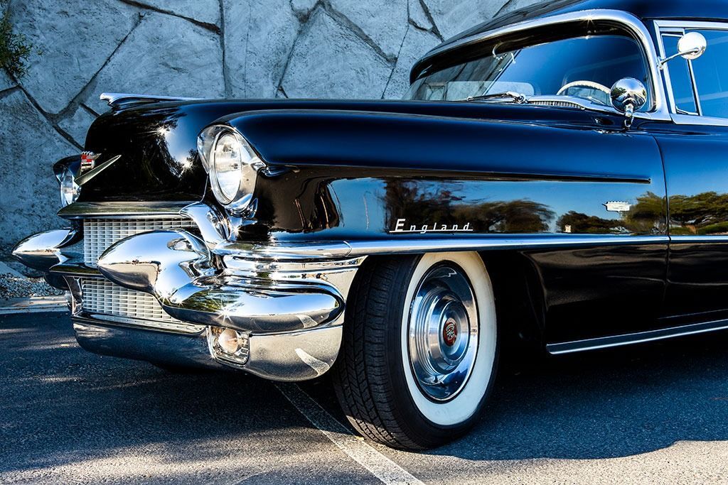 Black classic Cadillac with white-wall tires, chrome details, parked outside.