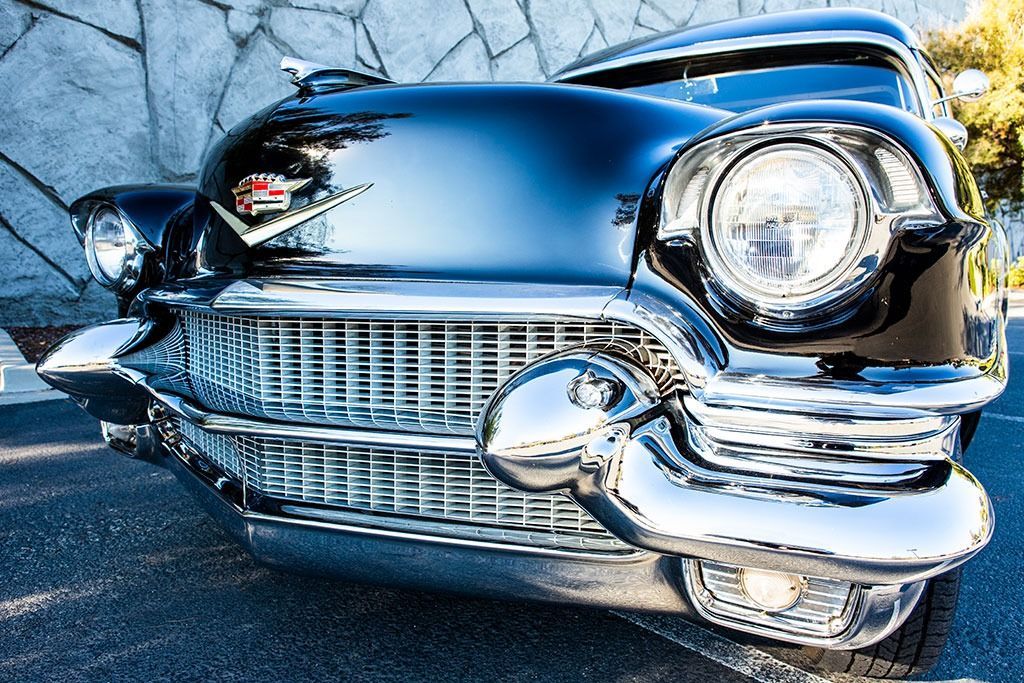 Shiny black vintage Cadillac with chrome grill and headlights.