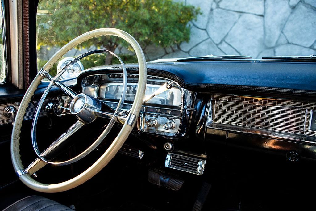Interior of a classic car, showing steering wheel, dashboard, and chrome details.
