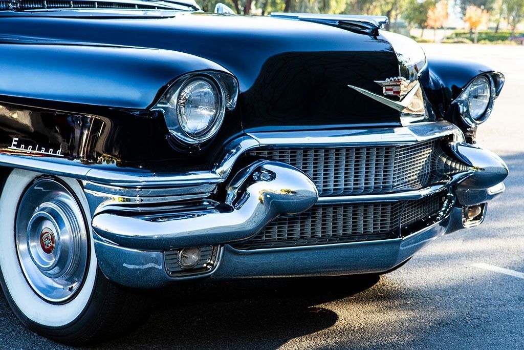 Black vintage Cadillac with chrome accents and white-wall tire, parked outdoors.