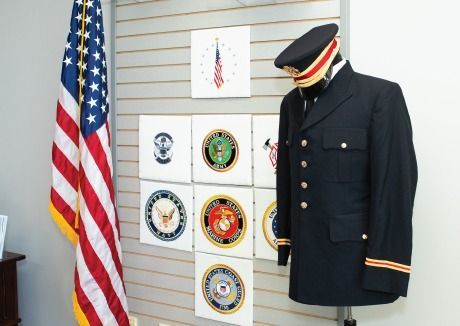 A woman is holding an american flag and a rose at a funeral.