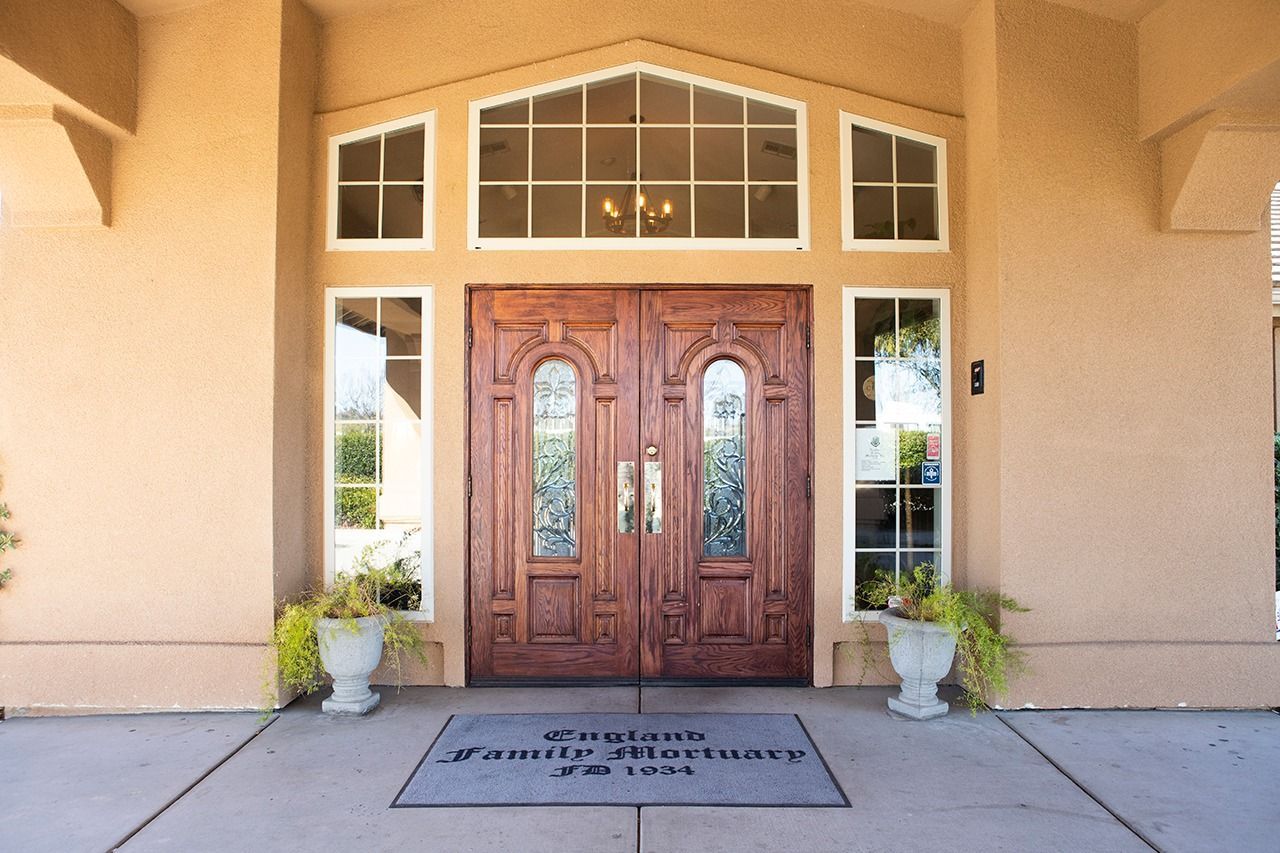 Wooden double doors with sidelights and transom window. Welcome mat: Coulter's Family Mortuary.