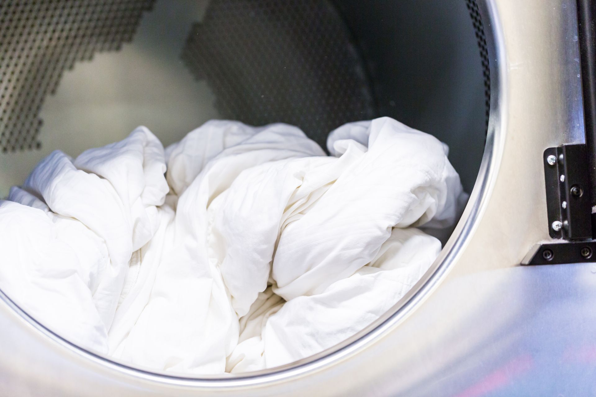 White laundry piled inside a front-loading washing machine drum White laundry piled inside a front-loading washing machine drum