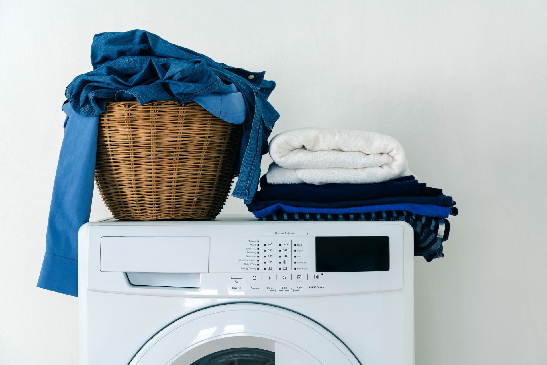 Laundry basket and folded towels on top of a front-loading washing machine Laundry basket and folded towels on top of a front-loading washing machine