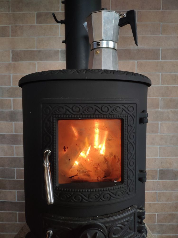 A Lit Wood-burning Stove With a Metal Moka Pot — Complete Heating In Huntingfield, TAS