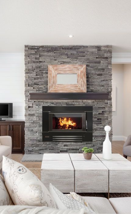 A lit Black Cast-iron Wood Stove Sits on a Hearth Pad — Complete Heating In Huntingfield, TAS