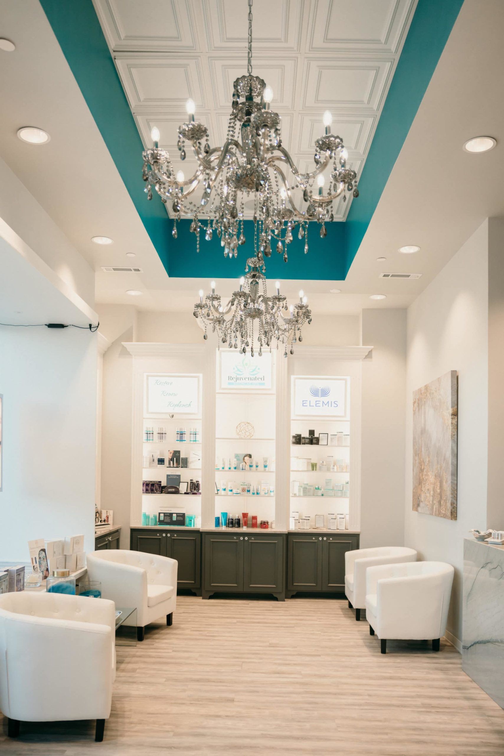 A waiting room with white chairs and a chandelier hanging from the ceiling.
