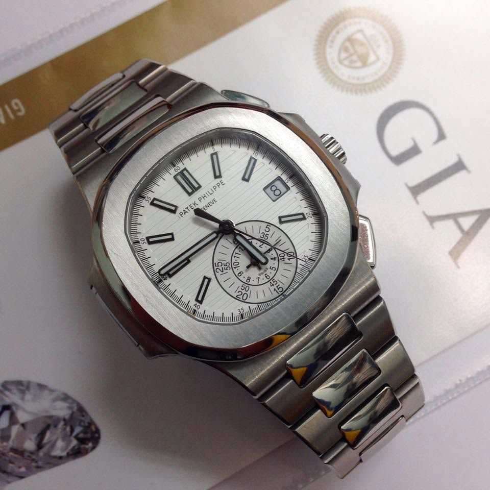 Silver wristwatch with white dial resting on a magazine page