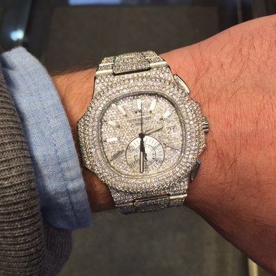 Close-up of a wrist wearing a diamond-encrusted watch with a silver band and white dial