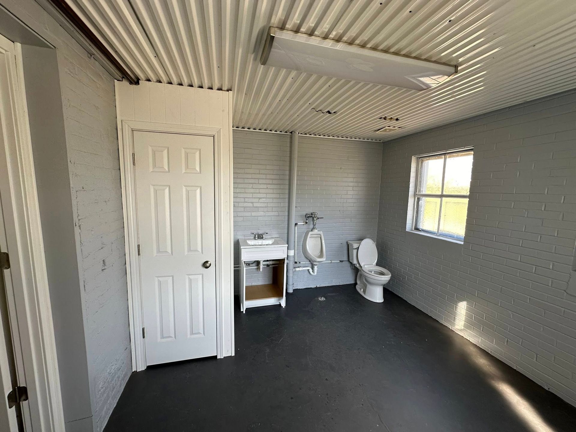 A bathroom with a toilet , sink and urinal.