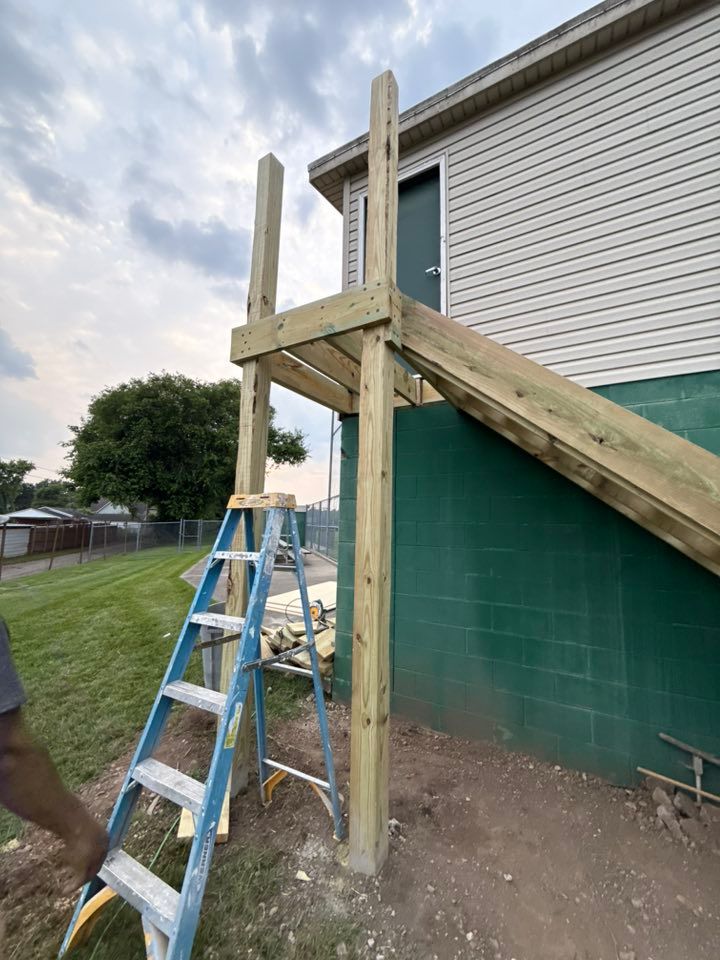 A man is standing next to a ladder in front of a house.