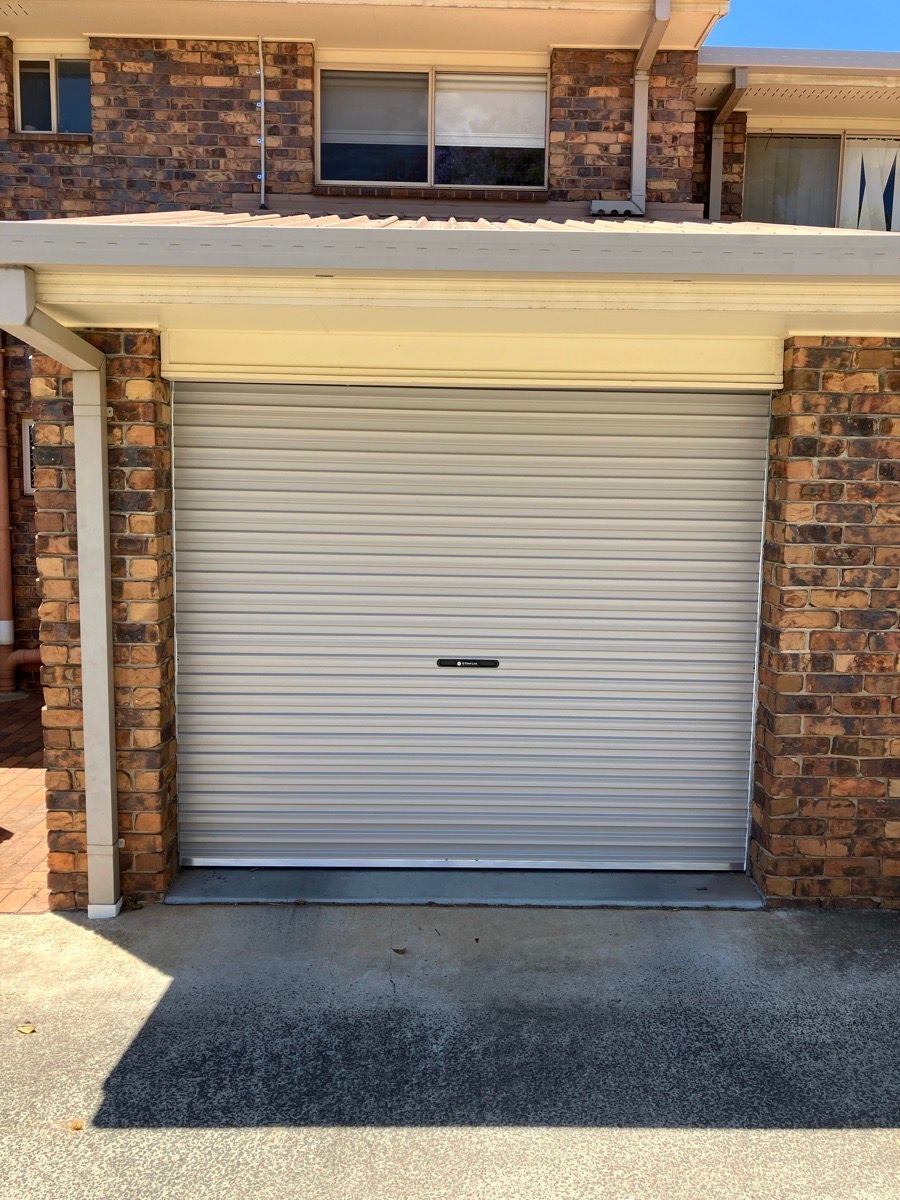A white garage door is sitting in front of a brick building in Toowoomba