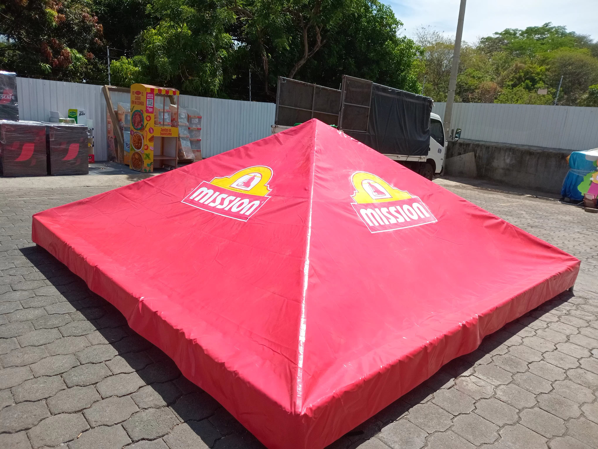 Carpa cuadrada de la marca Red Mission instalada en un área pavimentada al aire libre.
