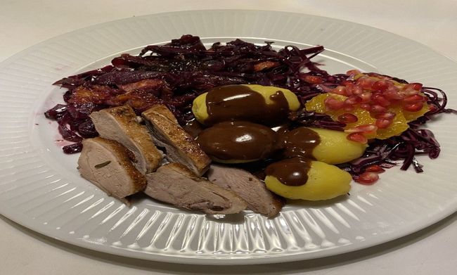 Et træbord fyldt med en række forskellige retter, herunder kartofler, salat, kød og oliven.