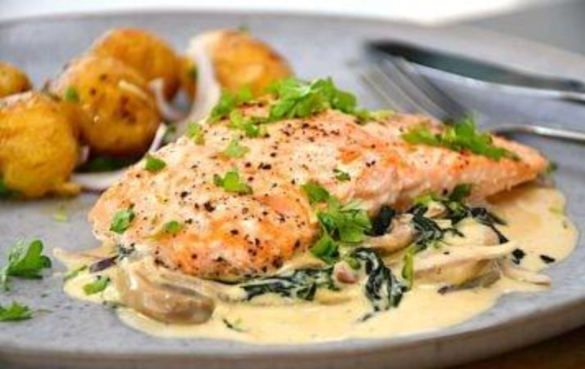 Et træbord fyldt med en række forskellige retter, herunder kartofler, salat, kød og oliven.