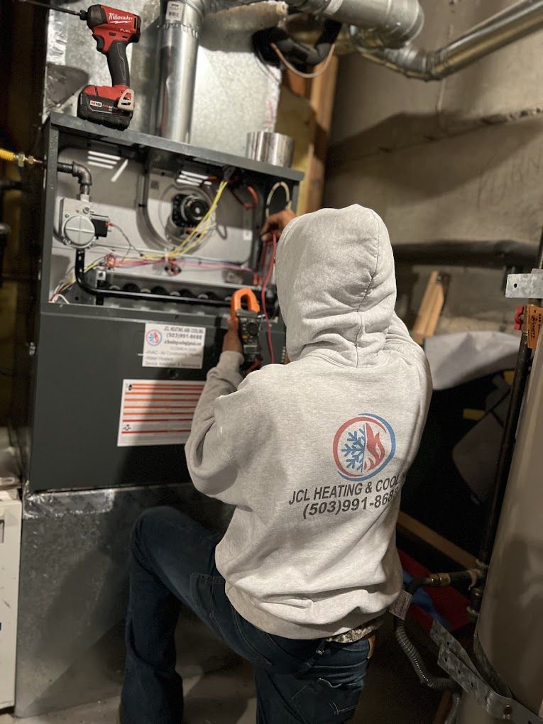 a man in a hoodie is working on an air conditioner in a basement .