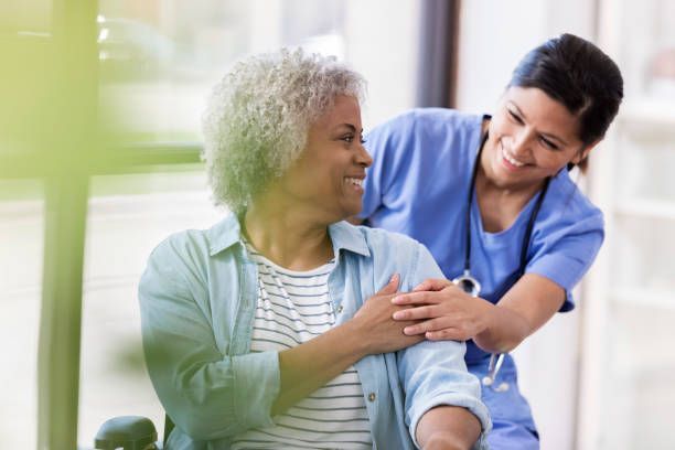A nurse is helping an elderly woman in a wheelchair.