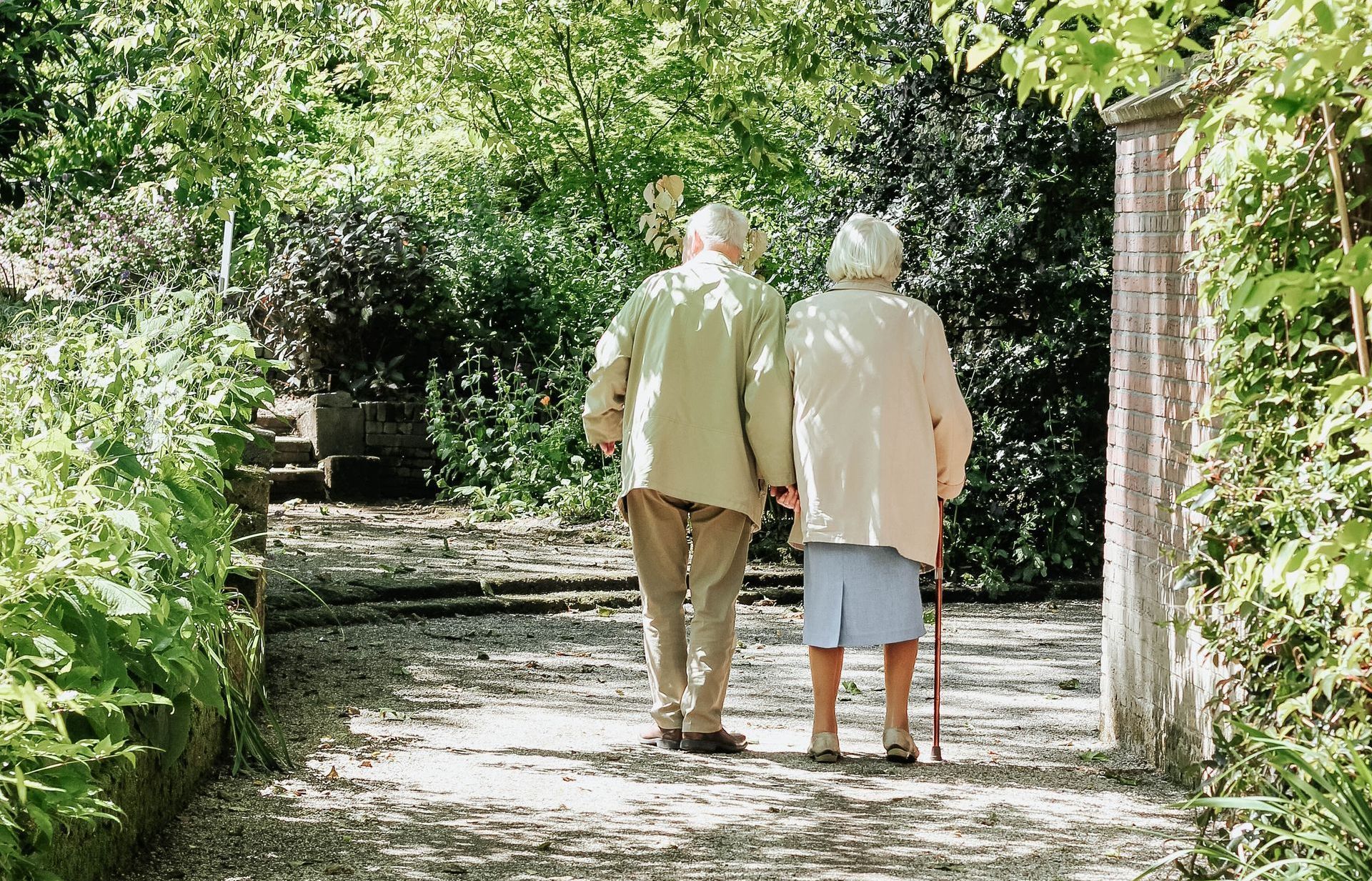 a man and a woman are walking down a path holding hands .