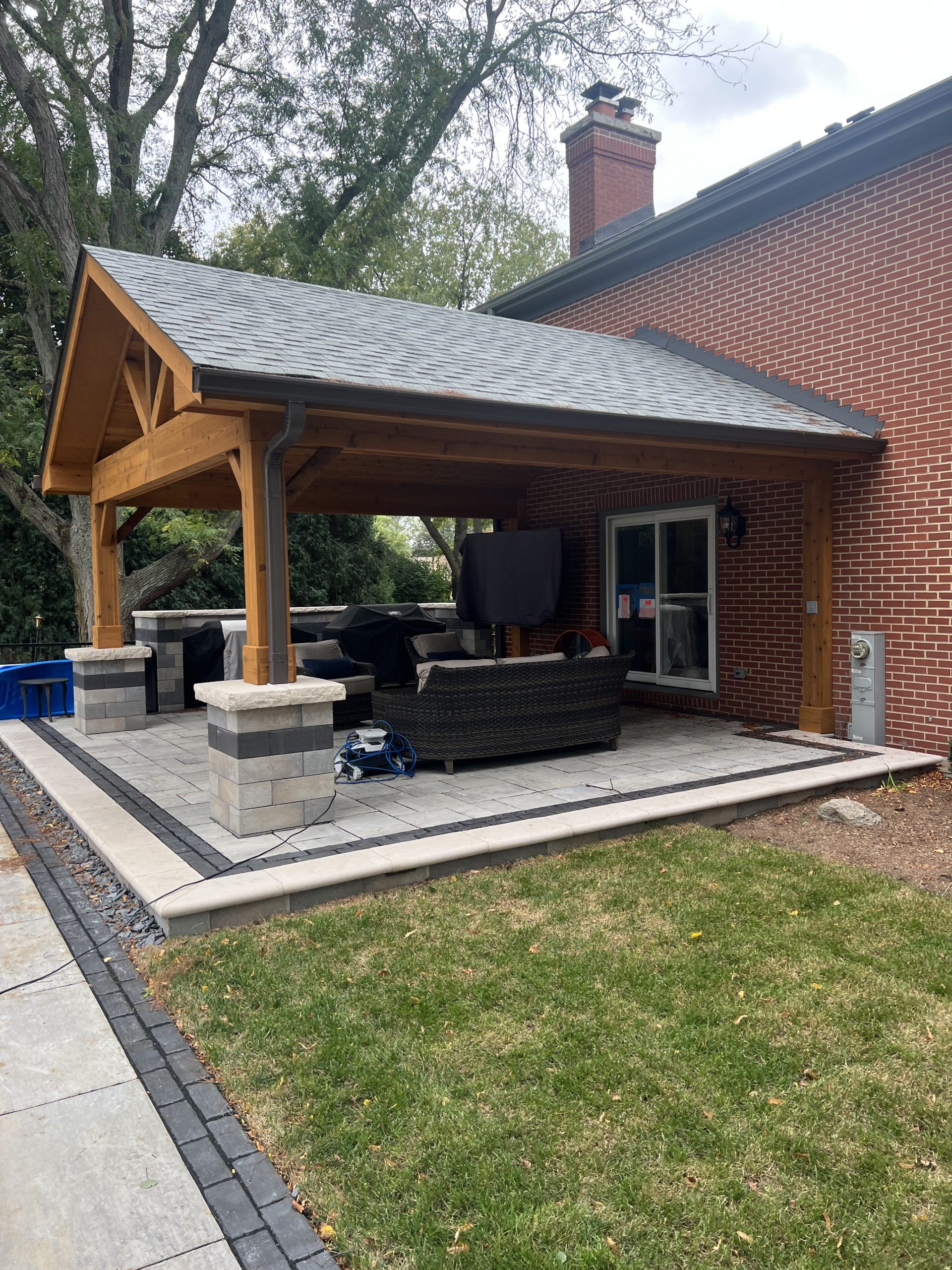 Outdoor patio with wooden pergola, built-in seating, and brick house.