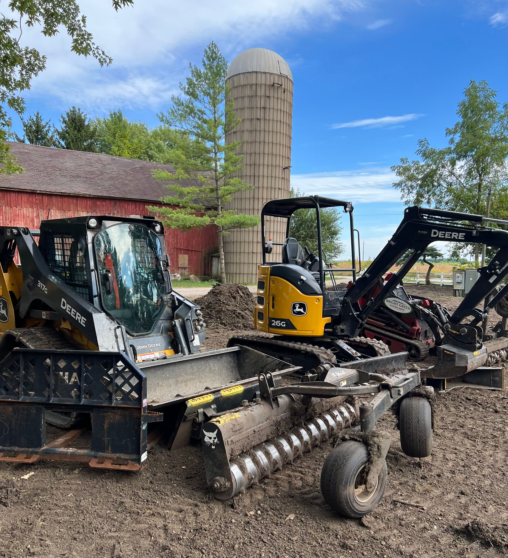 A backyard being prepared for landscaping by a yellow skid steer.