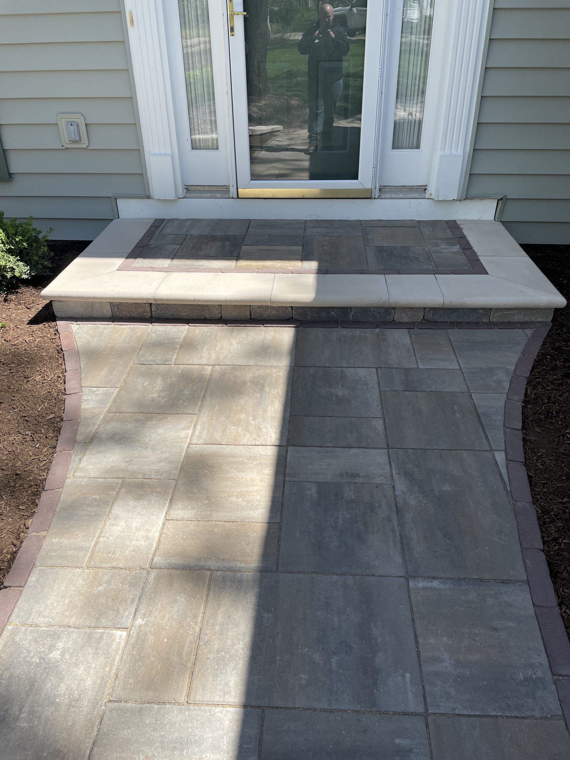 Stone walkway leading to a front door with a small porch, flanked by brown mulch.