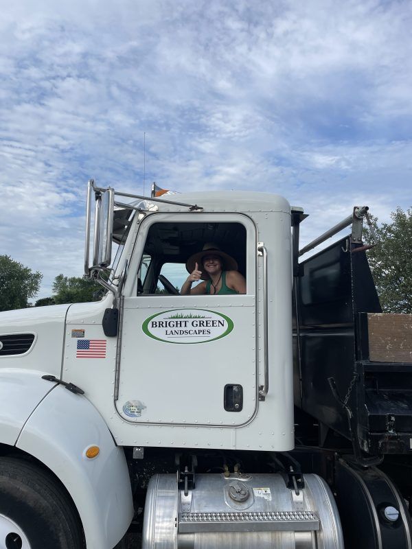 Woman in a white truck giving a thumbs up. Truck has 
