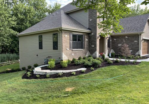House exterior with landscaped yard, stone accents, and green grass.
