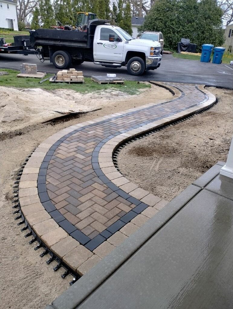 A newly constructed winding brick path with a truck in the background.
