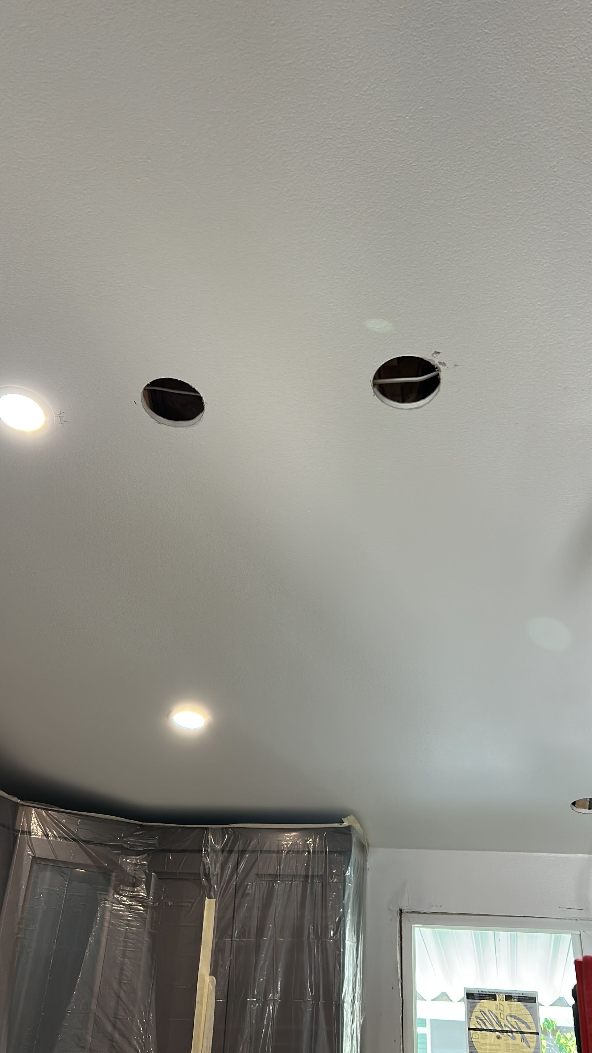 White ceiling with two circular cutouts and an illuminated recessed light fixture.
