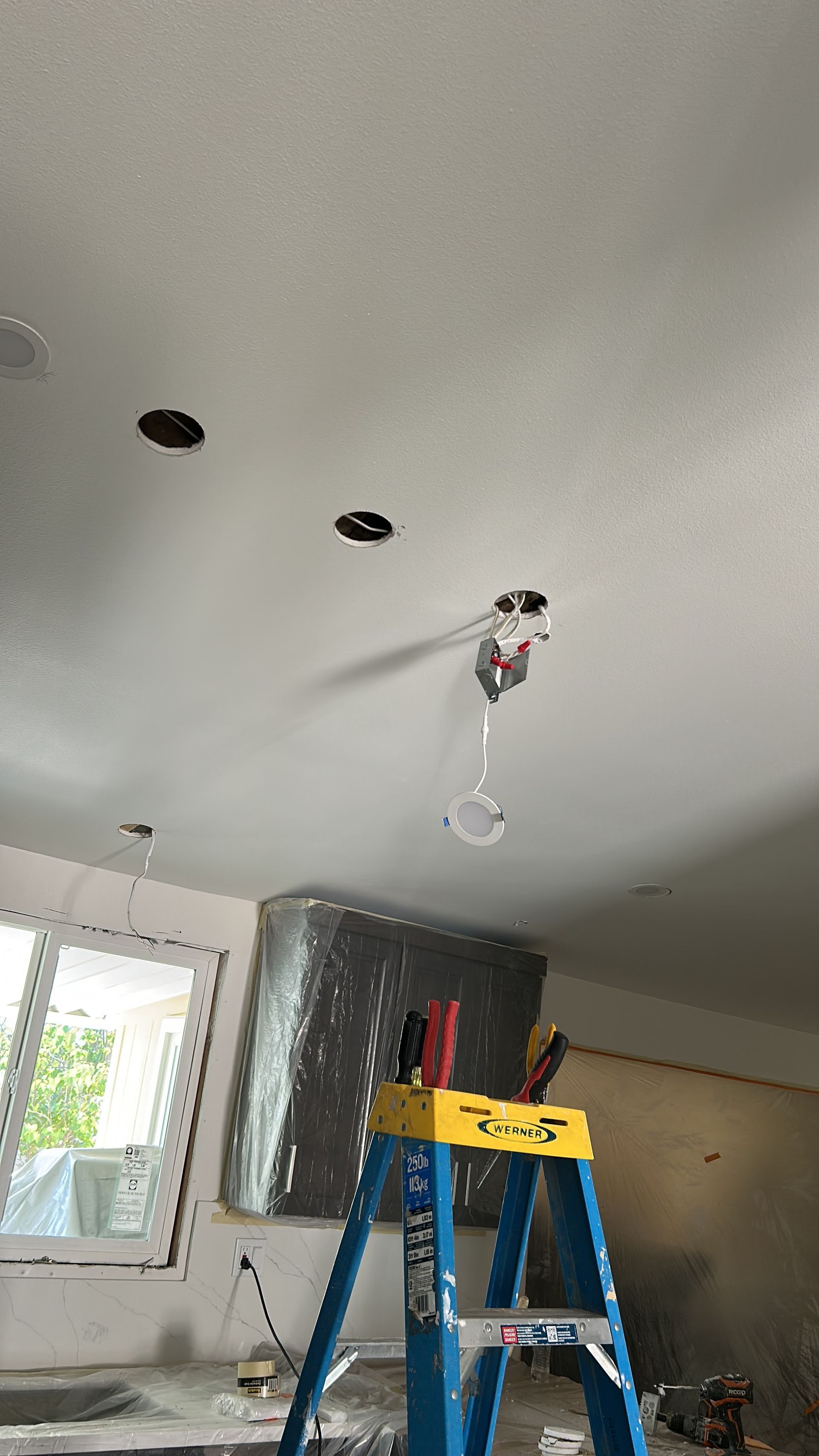 Blue house with red door and brick accents, SUV in driveway, basketball hoop.