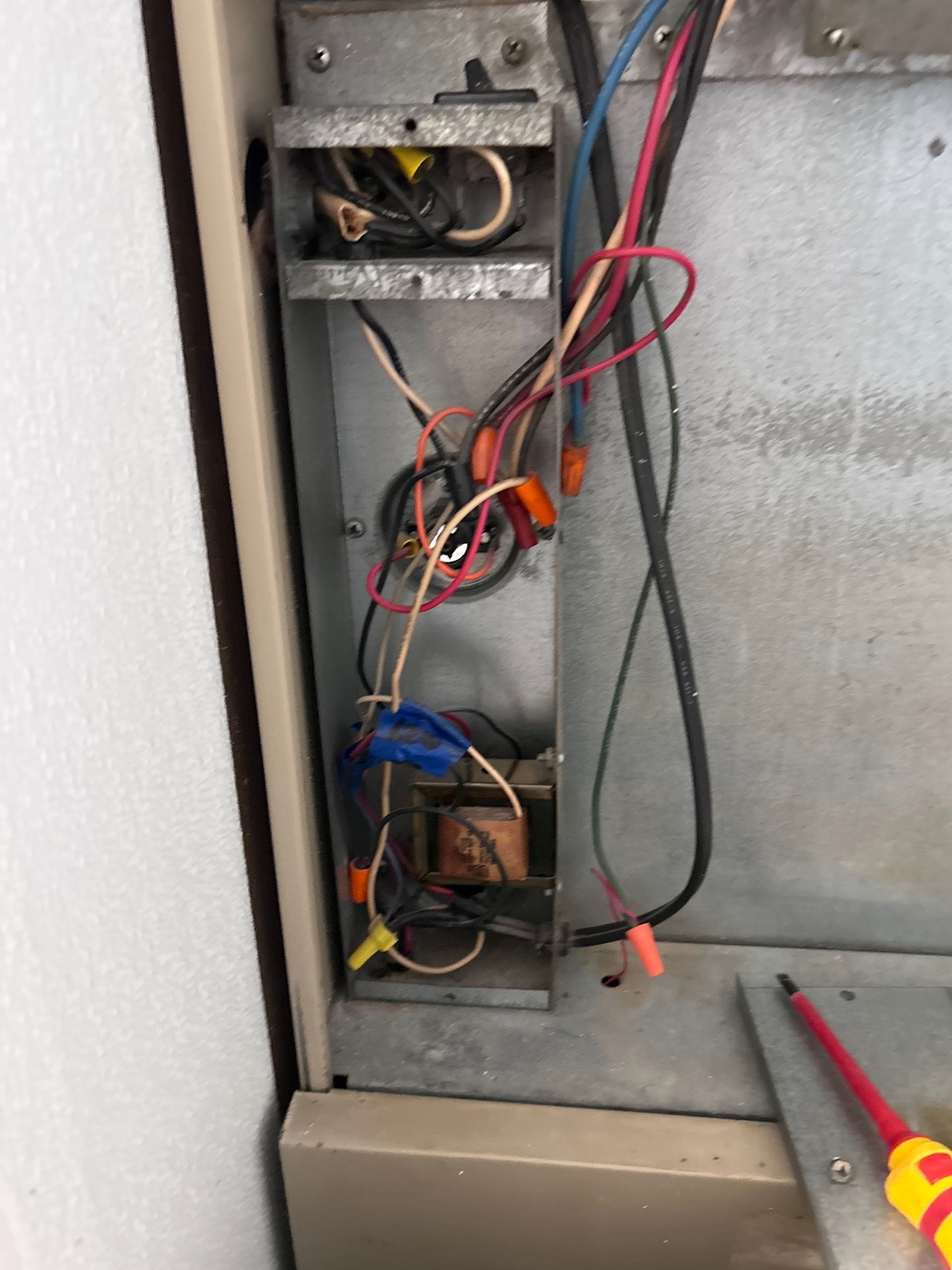 Two technicians in blue coveralls and hard hats operating machinery, one using a laptop.