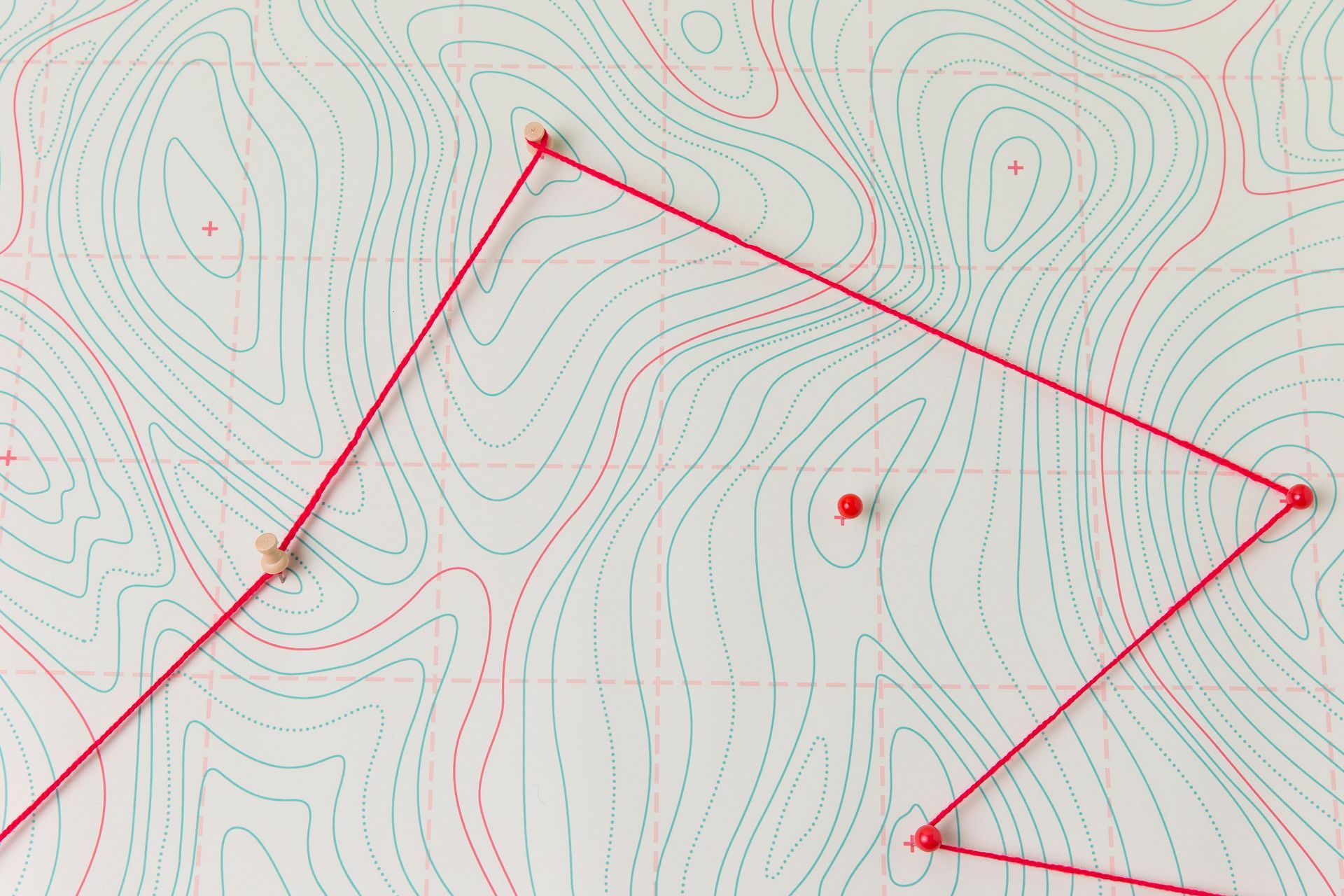 Raudona virvelė, jungianti smeigtukus topografiniame žemėlapyje su žaliomis ir raudonomis kontūrinėmis linijomis.