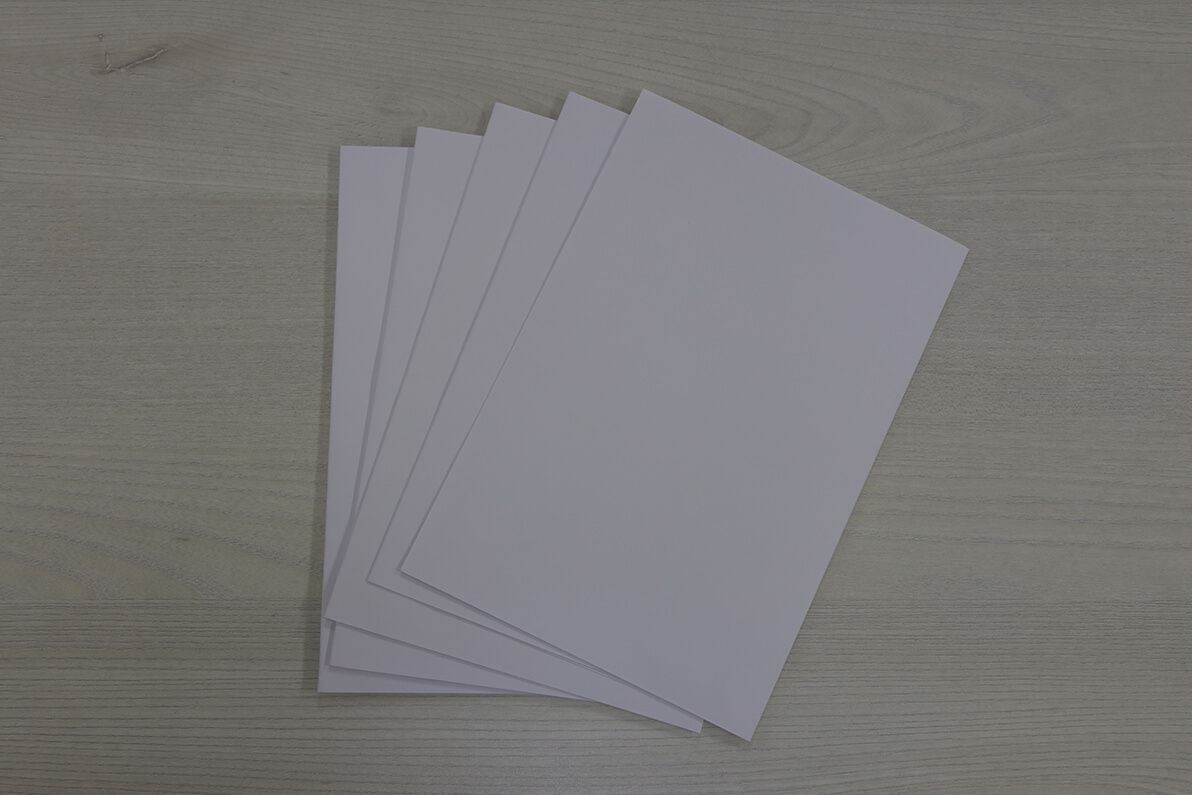 Five white sheets of paper are stacked on top of each other on a wooden table.