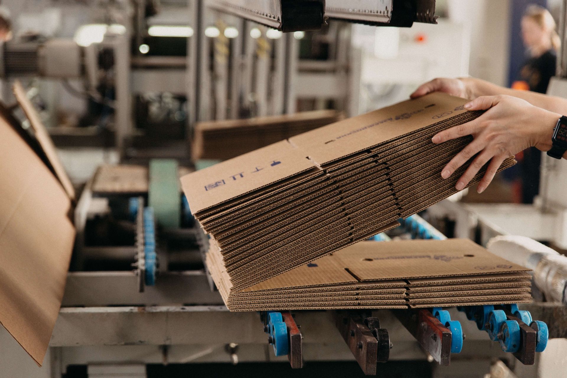 A person is holding a cardboard box in a factory