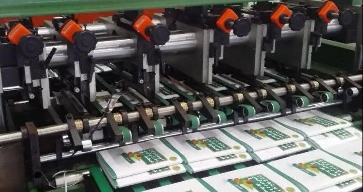 A machine is making a bunch of books on a conveyor belt