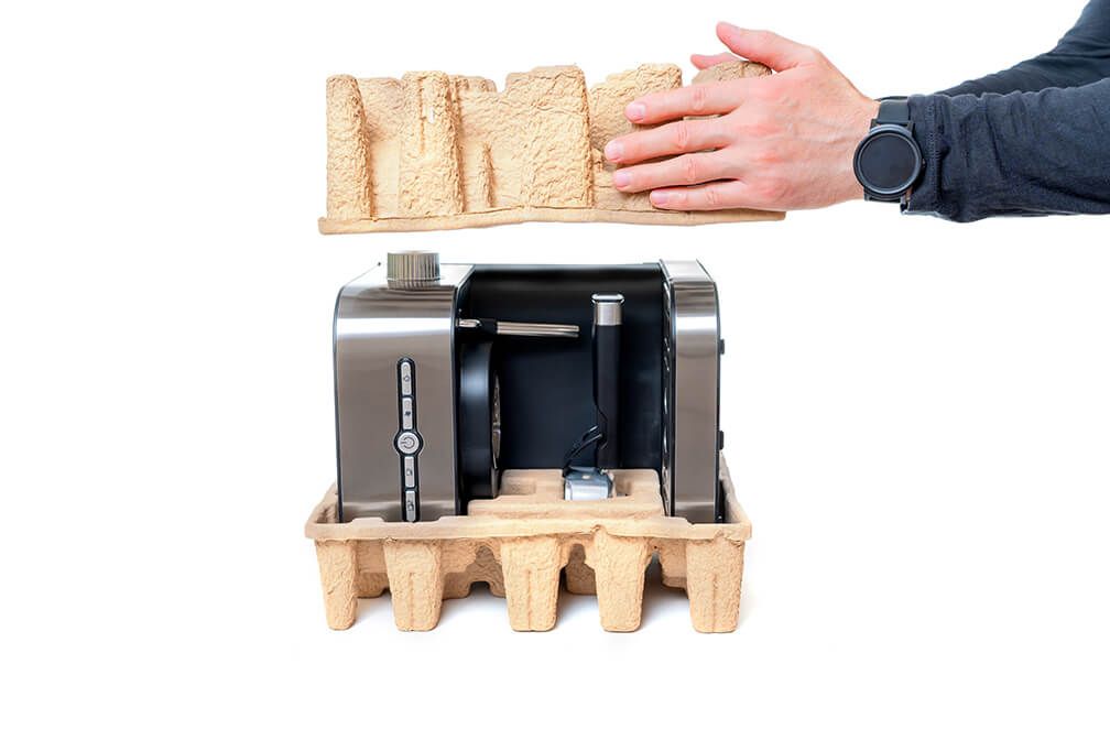 A person is holding a piece of wood over a toaster