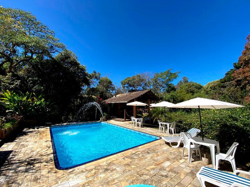 Piscina com fonte e guarda-sóis sob um céu azul brilhante.