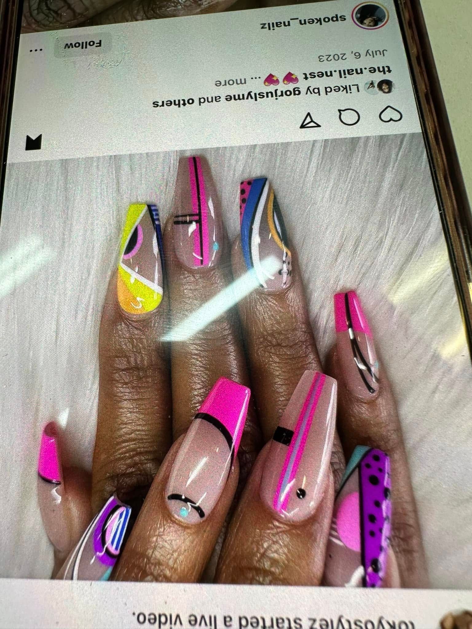 Long coffin-shaped nails with colorful, abstract geometric designs, bright pink accents, and clear-to-nude bases.