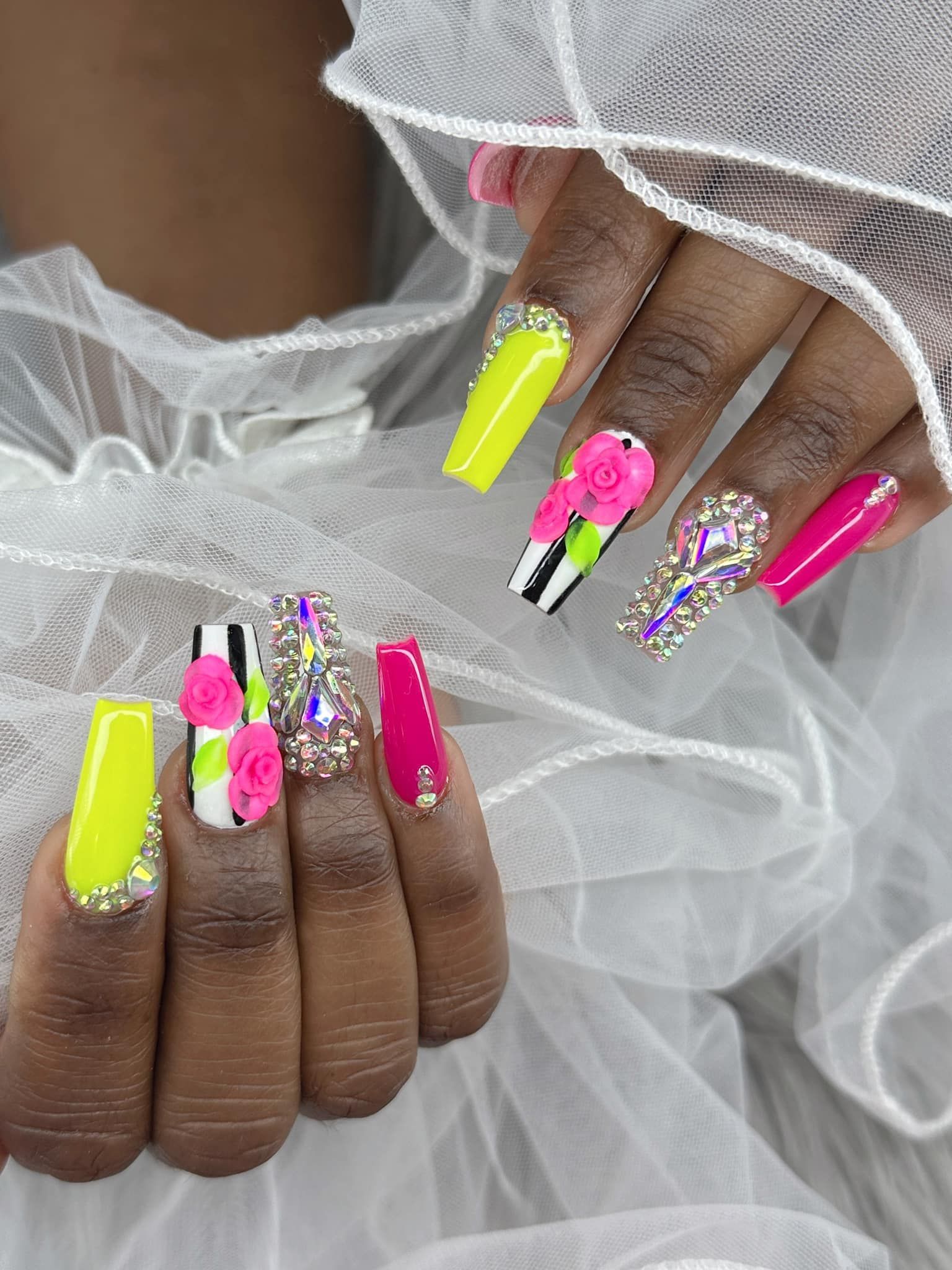 Manicured long square nails with neon yellow, hot pink, black-and-white stripes, 3D floral accents, and rhinestone jewels.